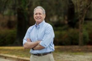 A college professor and researchers stands outside with arms crossed.