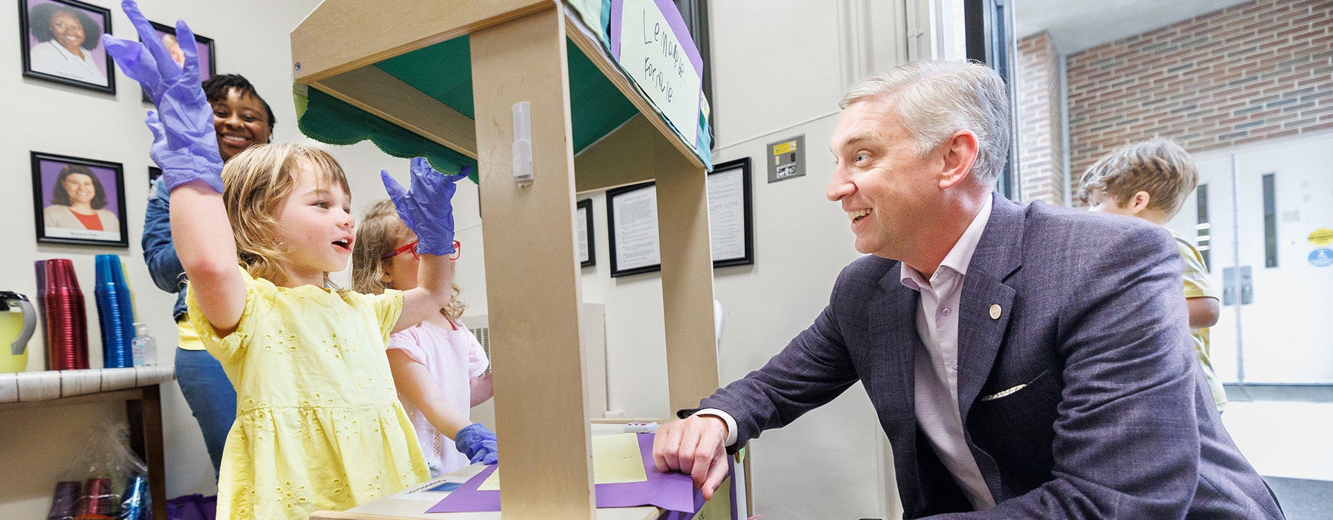 ECU Chancellor Philip Rogers smiles while visiting the Preschool 4 class lemonade stand to benefit Purple Pantry event held at the Nancy Darden Child Development Center.