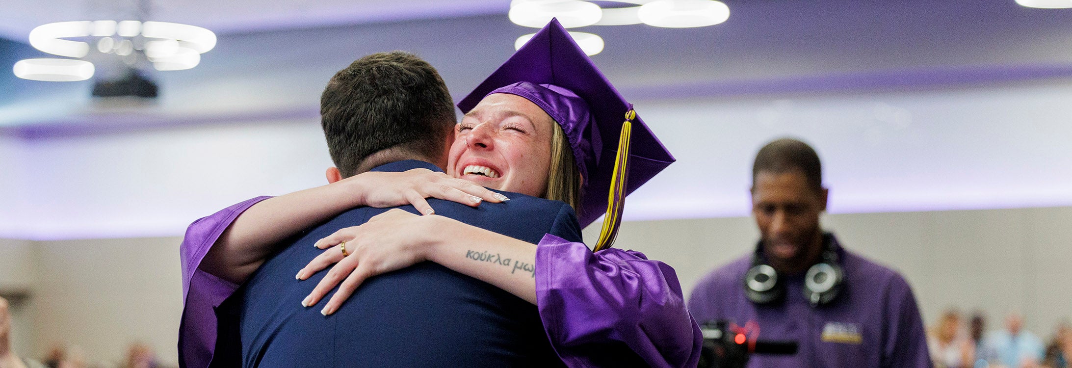 College graduate hugs her brother, who is wearing Coast Guard uniform.