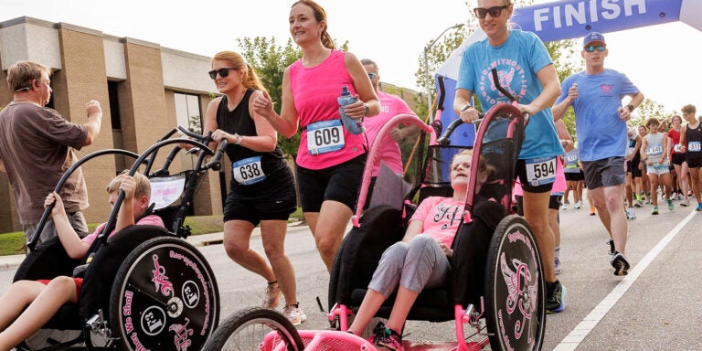 People walking in the street and pushing people in wheelchairs for a race event.