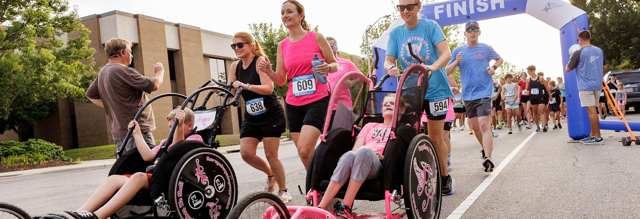 People walking in the street and pushing people in wheelchairs for a race event.