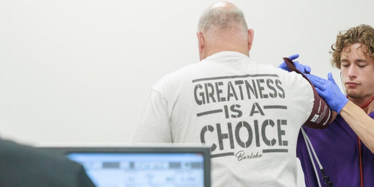 Student registering blood pressure of firefighter during an exercise stress test at the Human Performance Lab.