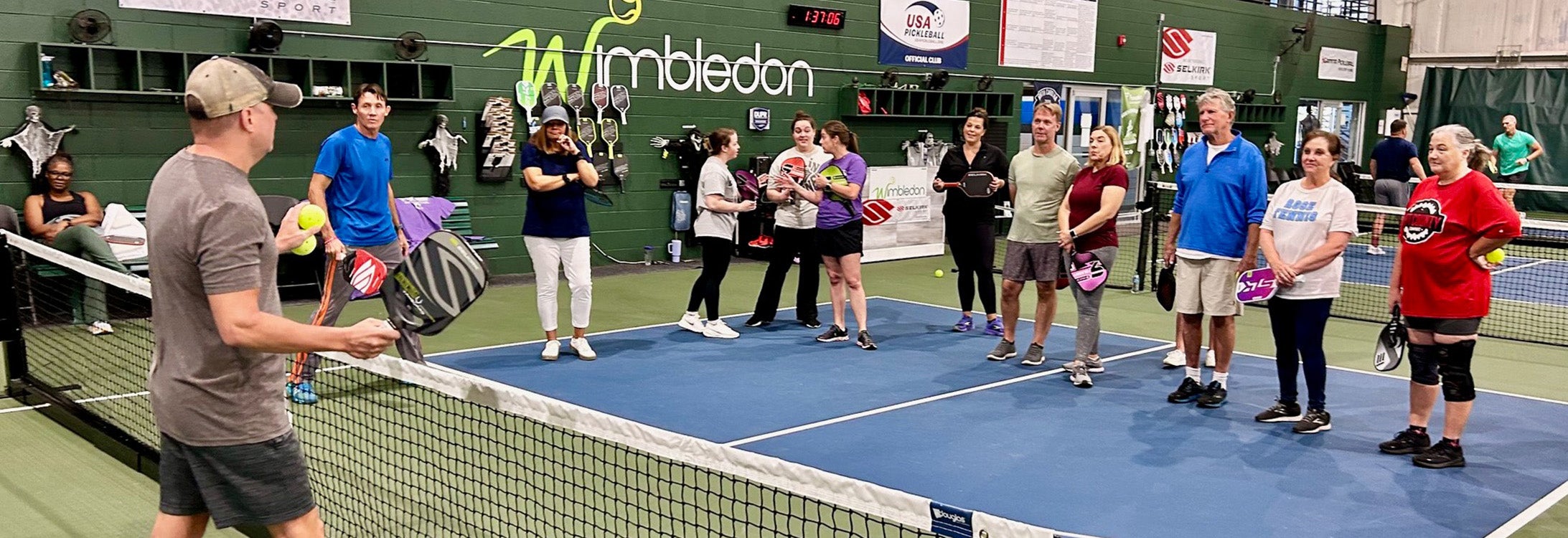 People standing and listening to instruction on pickleball court.