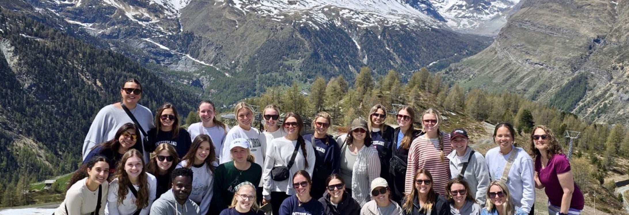 A group of college students with a mountain range in the background.