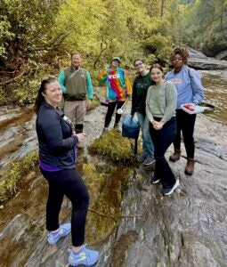 Group of people standing on rocks in a river.