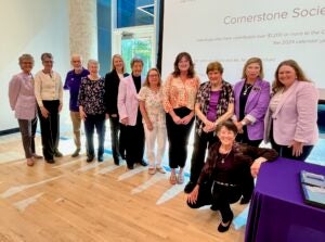 A group of people stand in front of a projector screen during awards ceremony.
