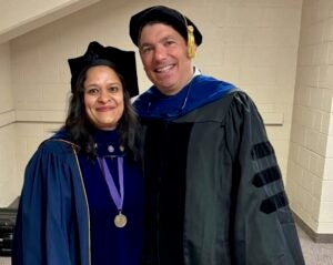 College faculty members stand together in black cap and gown clothing.