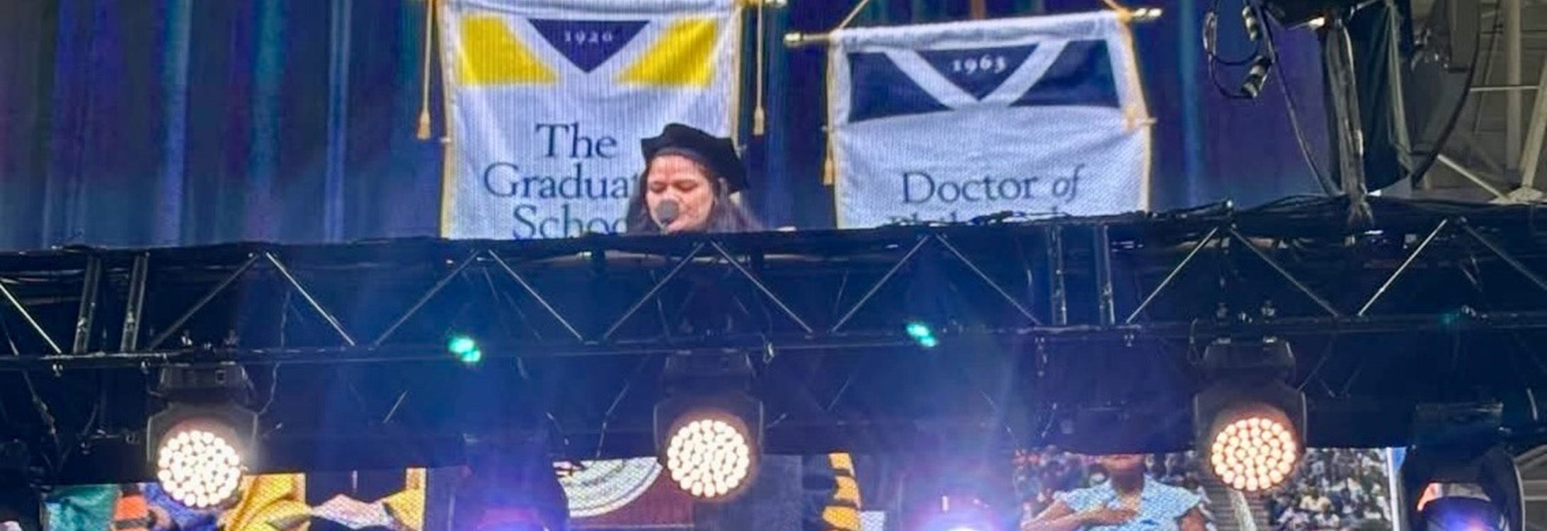 Faculty member Anu Hegde speaks at a podium during graduation event.