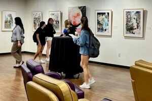 Social Work students look at the “Alzheimer’s Fantasies" art exhibit curated by Michael Dorsey in honor of his late wife, Susan. 