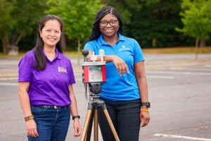 Dr. Jo Anne Balanay, left, stands with a heat stress monitor at the Belk Building during the summer of 2023.