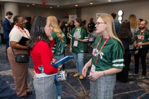 Students and job recruiters talking in large room.