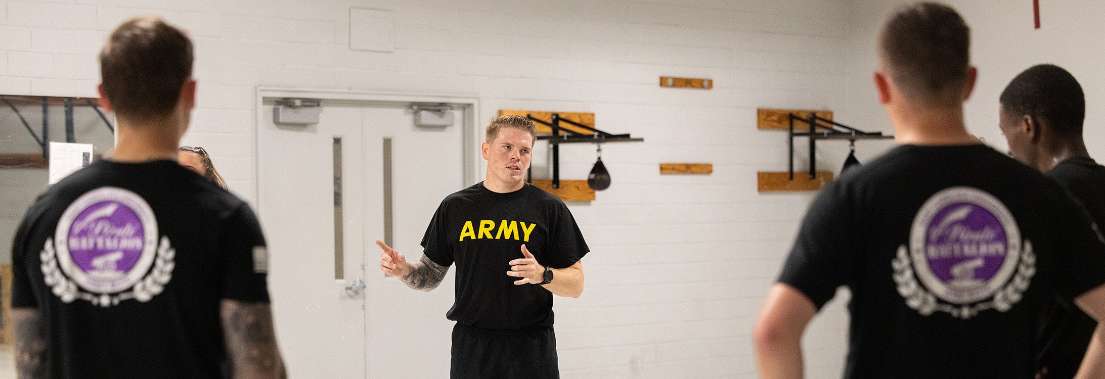 Four Army ROTC cadets stand in a room in conversation.