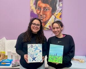 Two students hold their artwork.