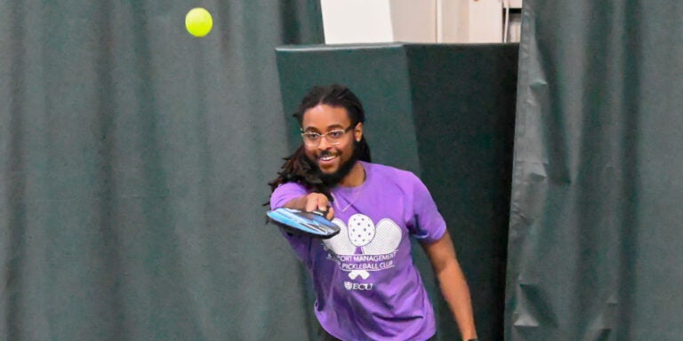 Darius Lawton watches as he hits the ball playing pickleball.