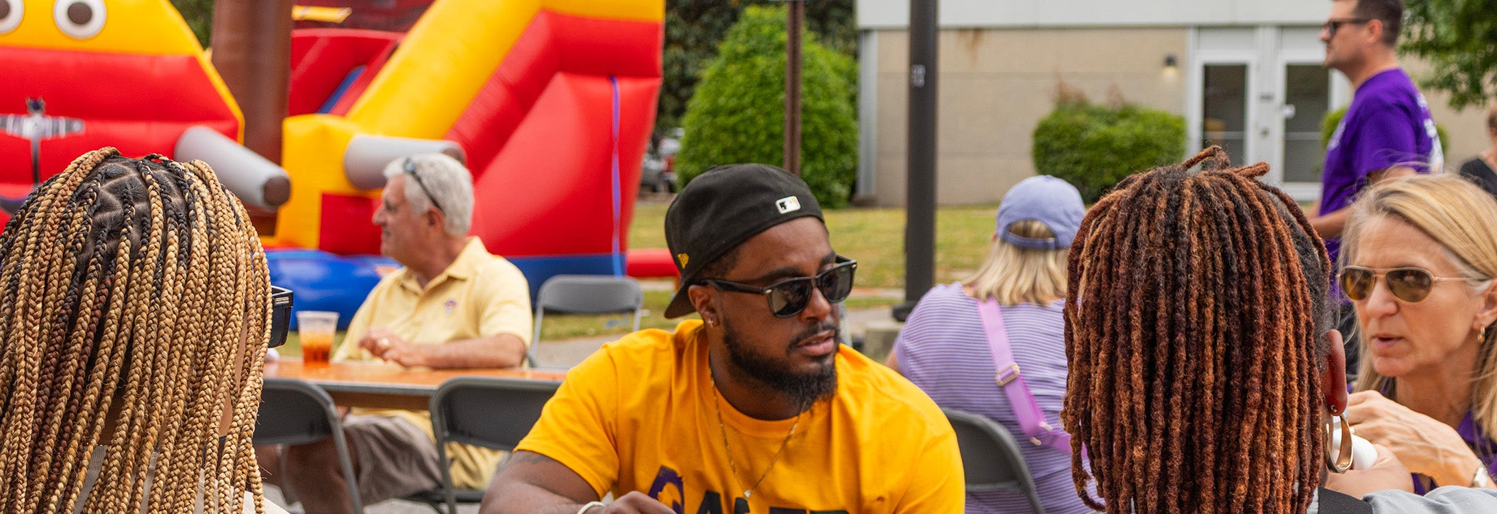 Group of people sitting outside talking during a tailgate event.